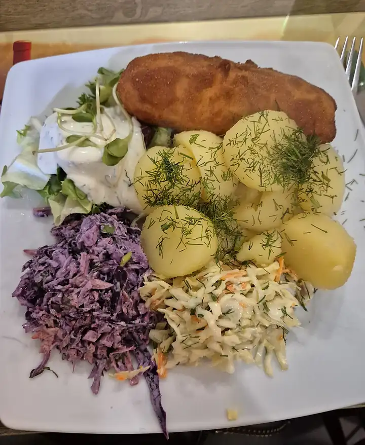 Kotlet schabowy z ziemniakami z koperkiem i trzema surówkami: z czerwonej kapusty, z białej kapusty i z marchewki
