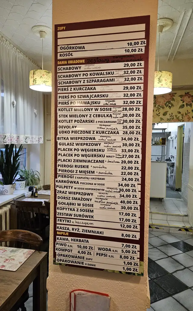 Bordowa tablica z białymi paskami cen w lokalu